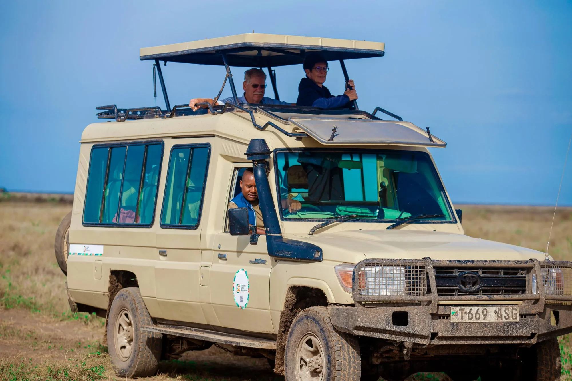 Véhicule de safari Land Cruiser à toit relevable garé devant un hôtel d'Arusha, prêt pour un départ matinal