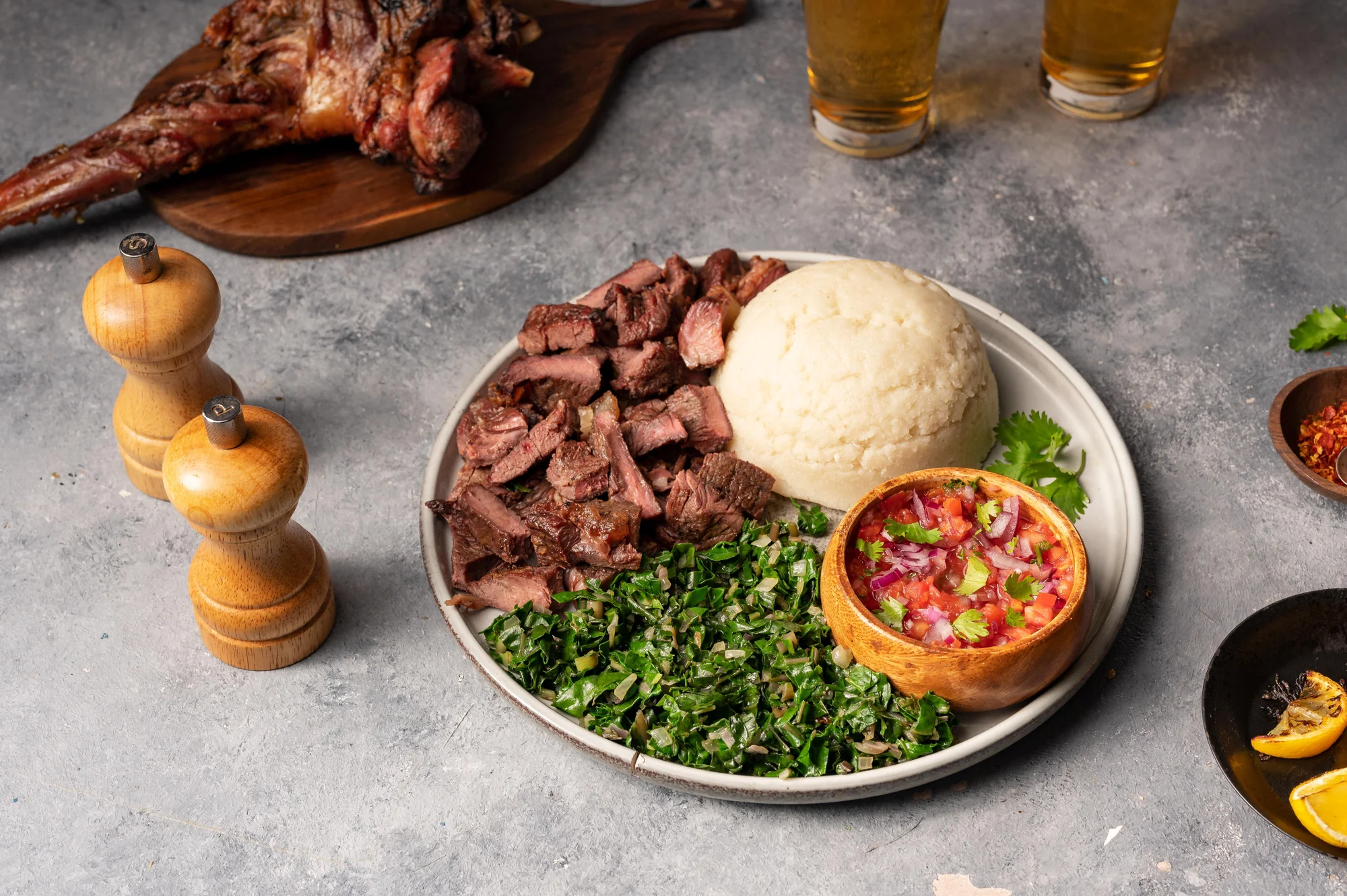 Assiette de nyama choma (viande grillée) avec ugali et légumes verts dans un restaurant local d'Arusha