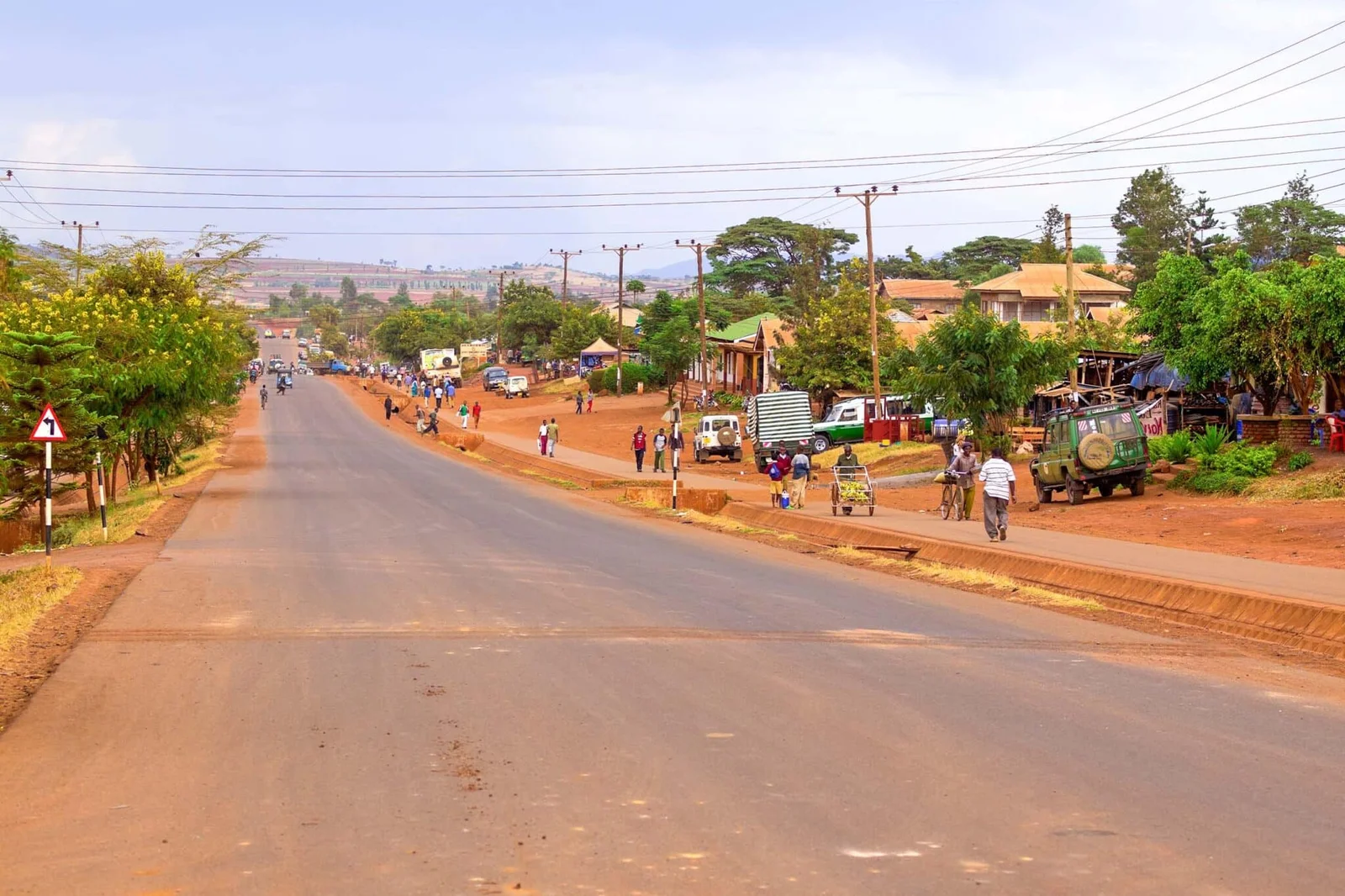 Route principale de la ville de Karatu avec des boutiques locales, une station-service et les hautes terres verdoyantes visibles en arrière-plan