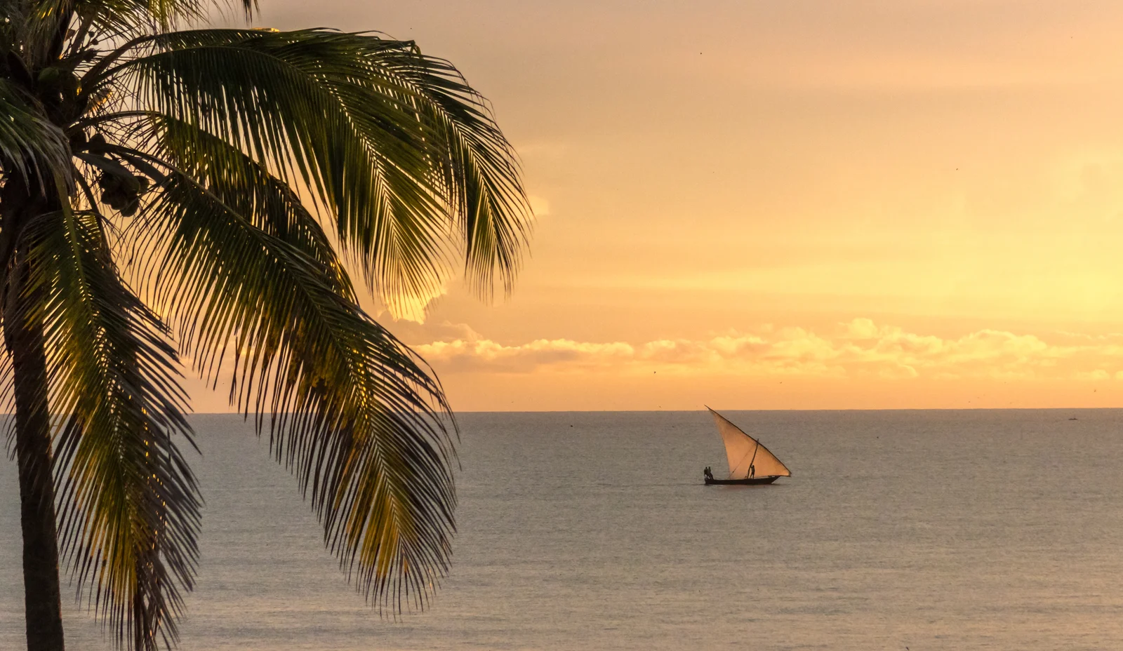 Dhow che naviga oltre Kilwa Kisiwani attraverso le acque turchesi del canale