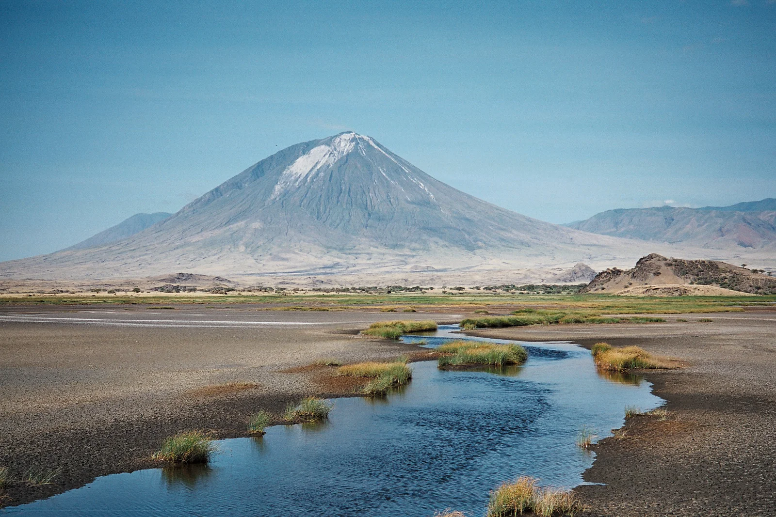 Véhicule de safari 4x4 sur la piste en tôle ondulée menant au lac Natron, avec l'Ol Doinyo Lengai se dressant au loin