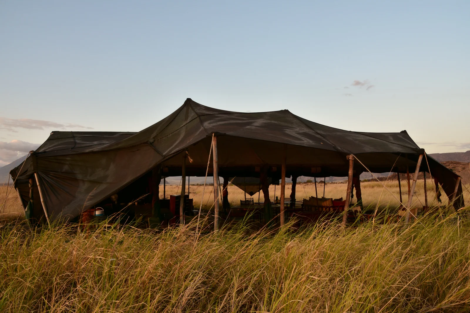 Les structures en toile du Lake Natron Camp, avec une ombre d'acacia clairsemée et le lac rouge au-delà