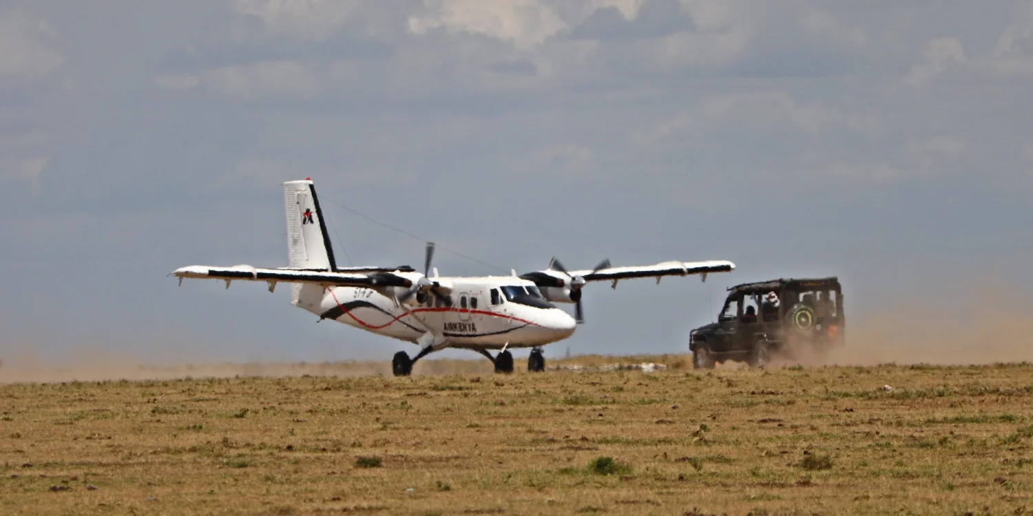 Una pista d'atterraggio del Mara all'alba — un aereo Caravan sullo sterrato, personale della comunità Maasai che carica i bagagli, l'arrivo standard nella destinazione safari più raggiunta in aereo del Kenya.