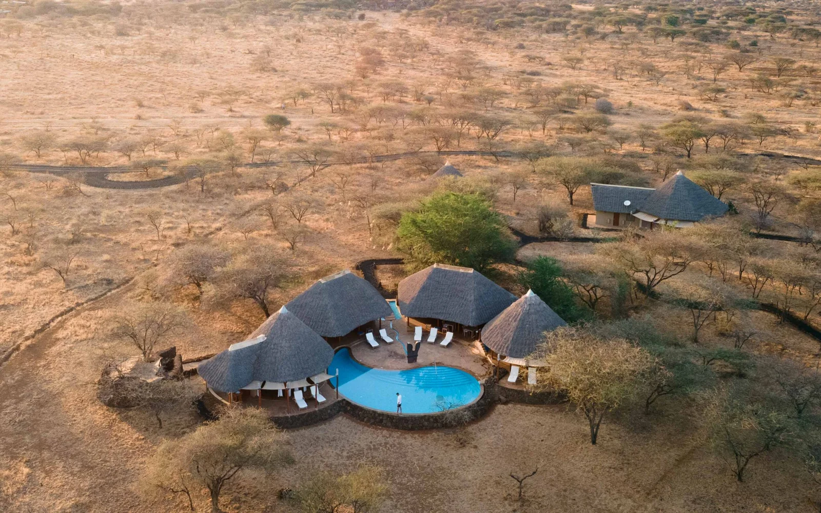 Luftaufnahme der roten Laterit-Ebenen von Tsavo, die sich bis zum Horizont erstrecken, mit dem Höhenzug des Yatta-Plateaus am westlichen Rand