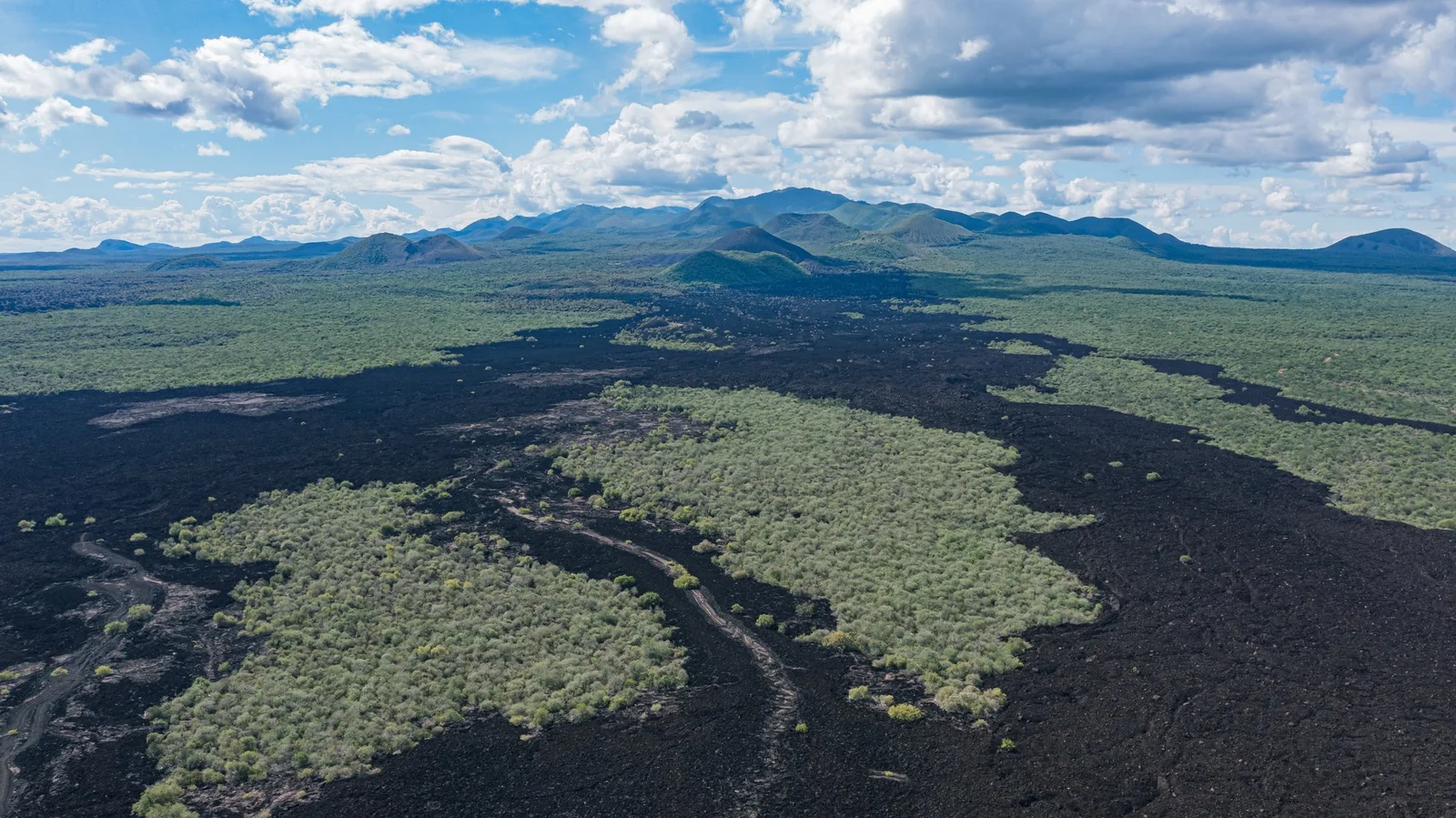 Le basalte noir de la coulée de lave de Shetani, avec les Chyulu Hills se dressant au loin en arrière-plan