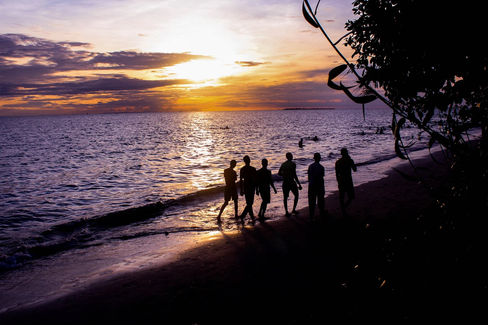 Atardecer sobre la playa de Nungwi con siluetas de dhows y bañistas vadeando en las cálidas aguas poco profundas de la costa norte