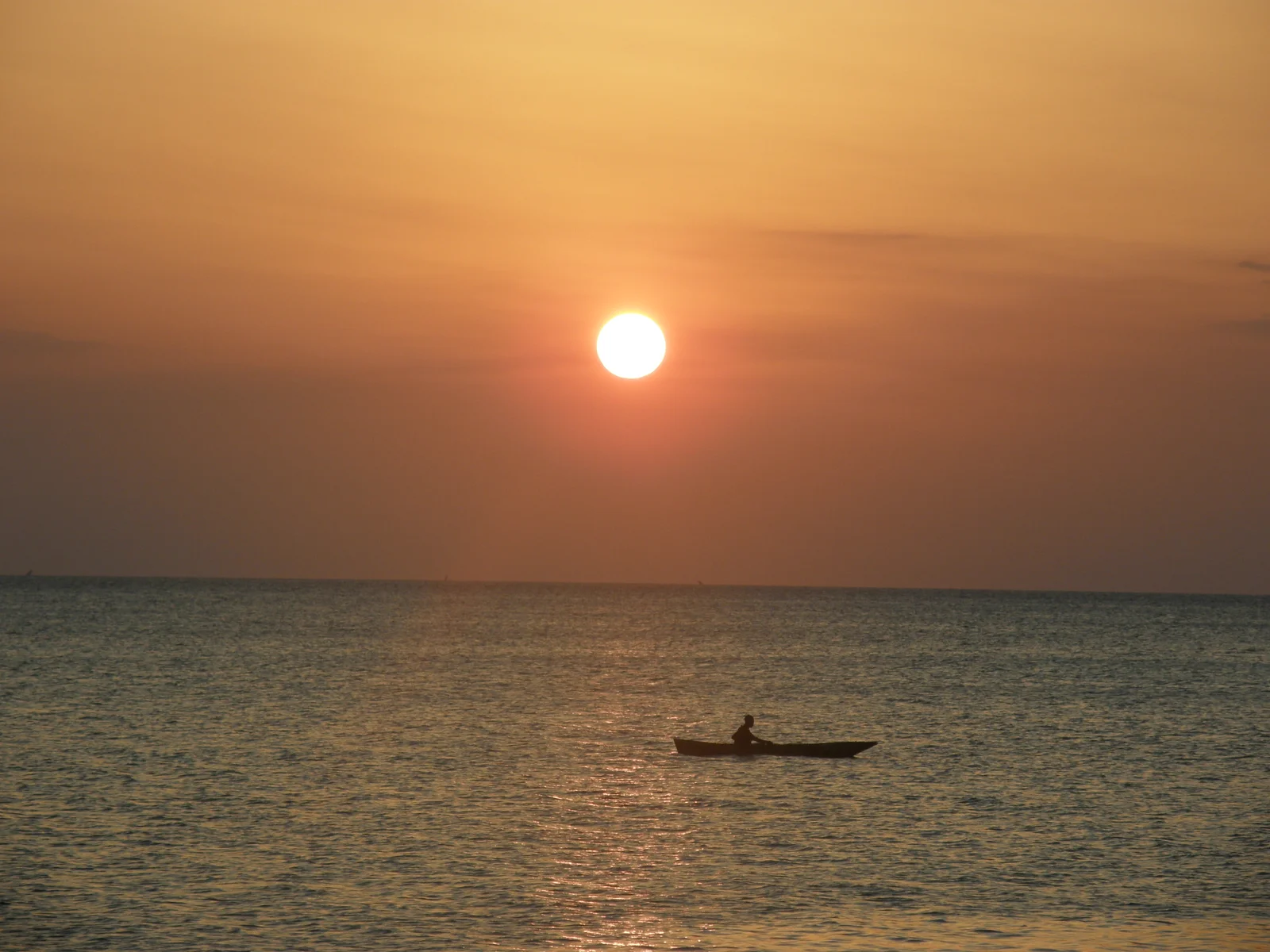 Atardecer en Kendwa con luz dorada sobre la arena blanca y un dhow solitario