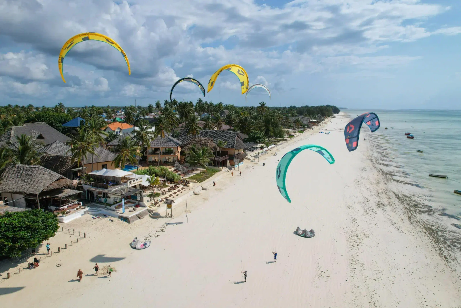 Vista panorámica de la playa de Paje en la hora dorada con decenas de cometas de colores en el cielo y kitesurfistas surcando la laguna turquesa poco profunda