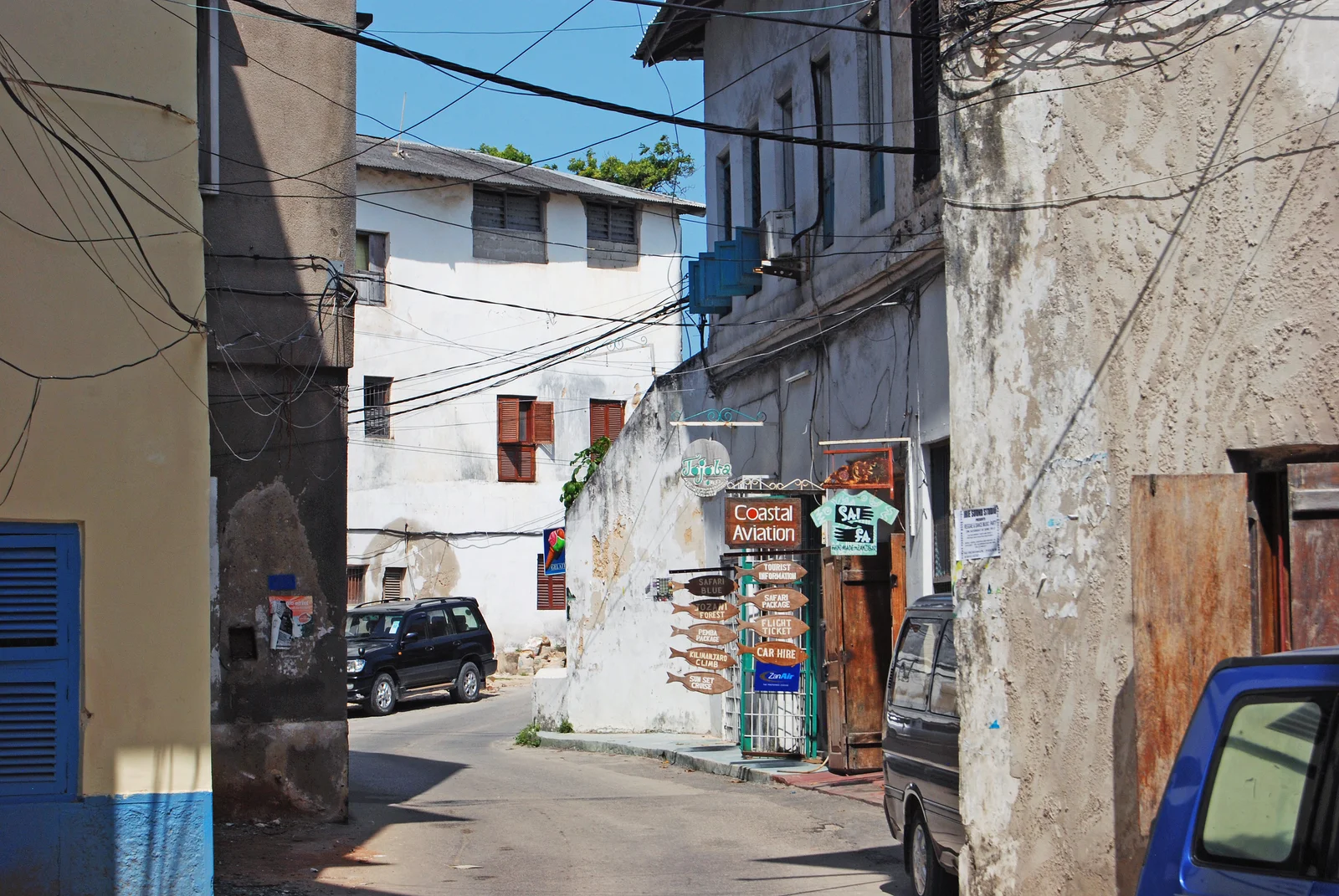 Callejón de Stone Town lavado por la lluvia, con charcos que reflejan las paredes de piedra coralina durante las lluvias largas